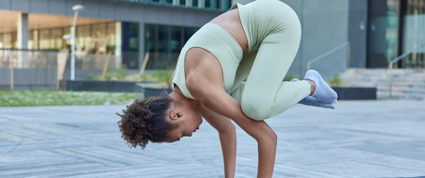 Woman performing an advanced balance exercise outdoors