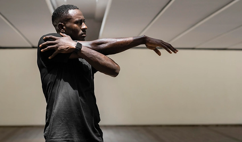Man performing shoulder mobility exercises indoors