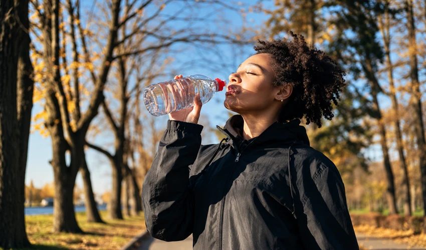 Woman drinking water outdoors during a walk