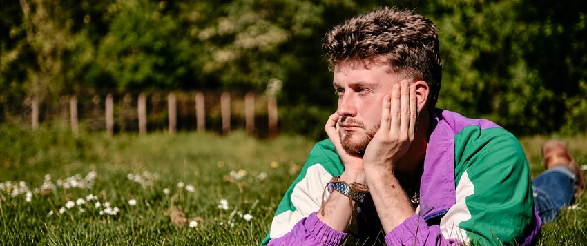 Tired man resting on grass outdoors during spring